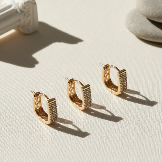 Gold hoop earrings with embedded stones on a light surface