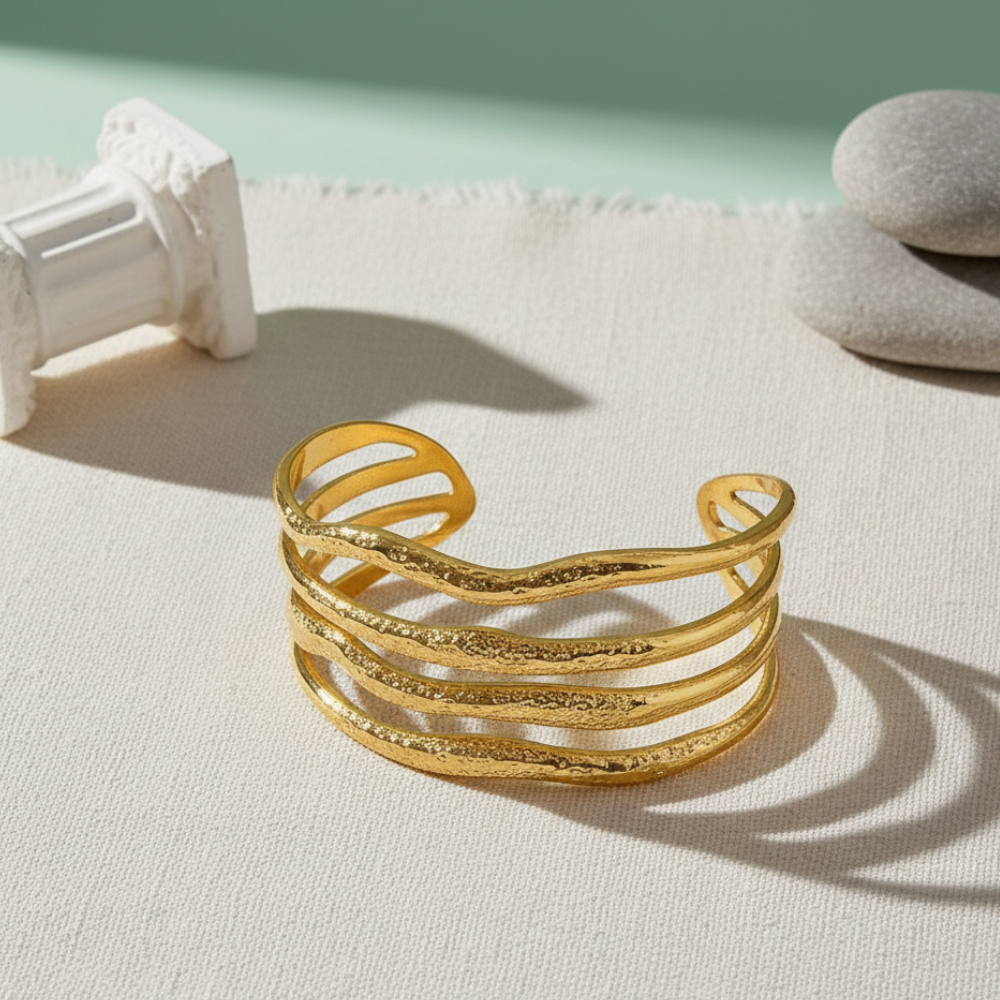 Gold bracelet on a light surface with a minimal background