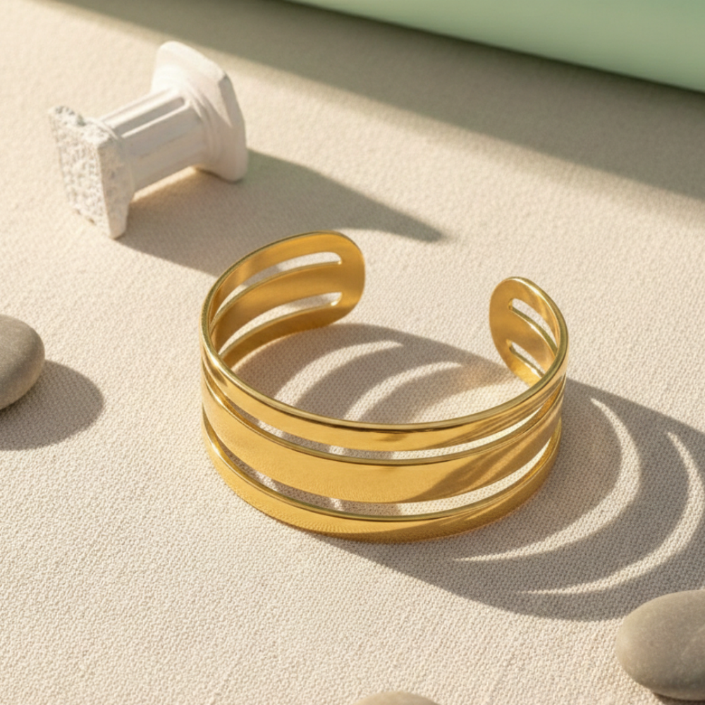 Gold bracelet on a textured surface with soft shadows
