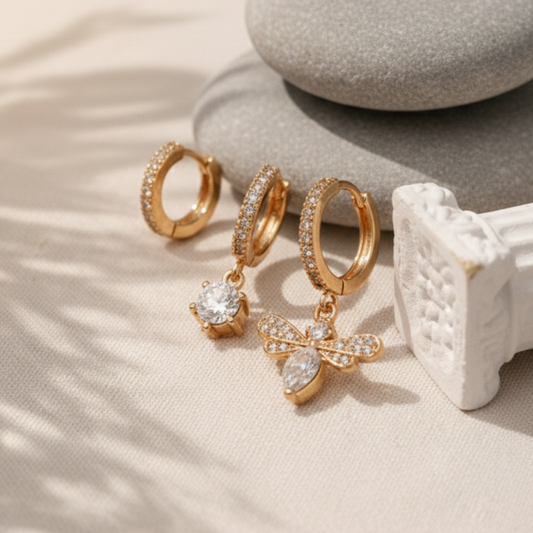 Gold hoop earrings with butterfly charm on a neutral background