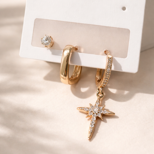 Gold hoop earrings with starfish charm on a white card against a beige background