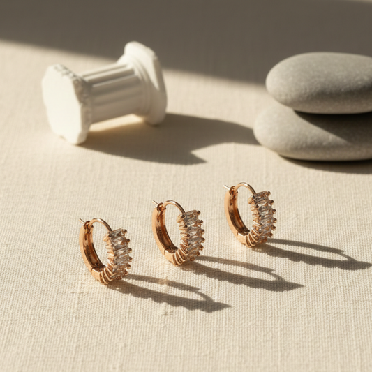 Set of gold hoop earrings on a textured surface with a neutral background