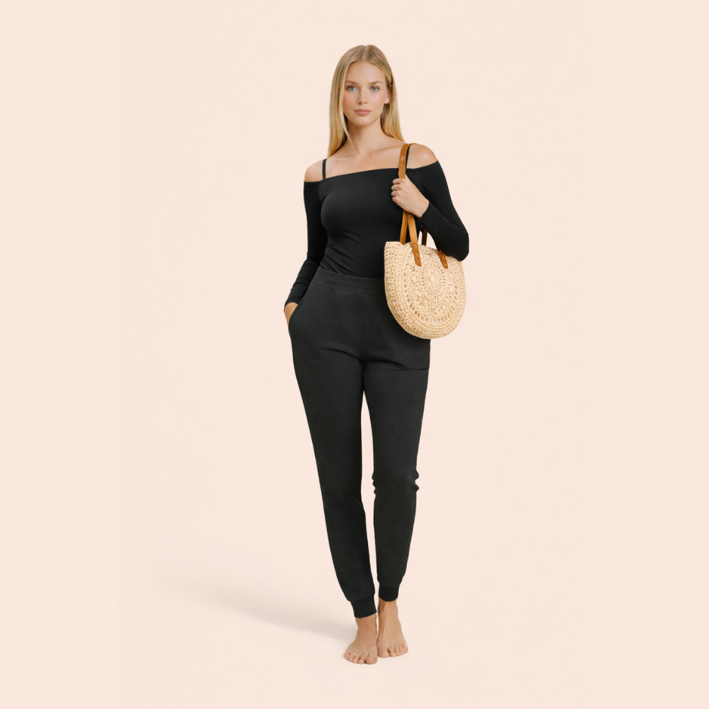 Woman wearing a black outfit holding a straw bag on a beige background