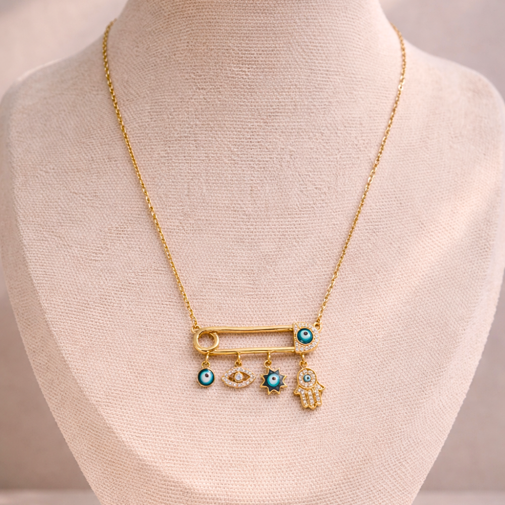 Gold necklace with safety pin pendant charms on a mannequin bust