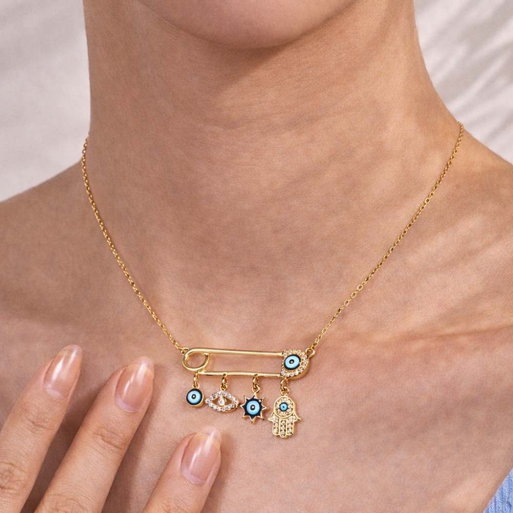 Gold necklace with safety pin charms on a person's neck
