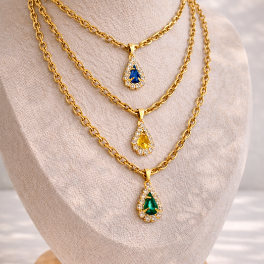 Three gold necklaces with teardrop-shaped gemstones on a mannequin bust.