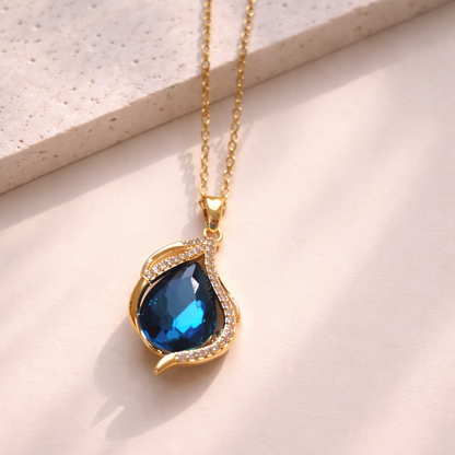 Gold necklace with a blue gemstone pendant on a light background