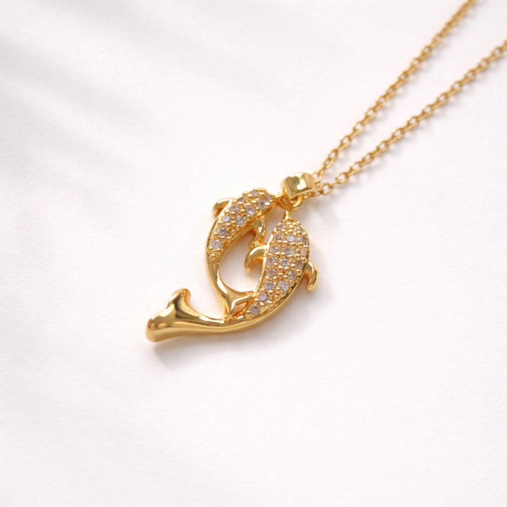 Gold dolphin pendant necklace on a white background