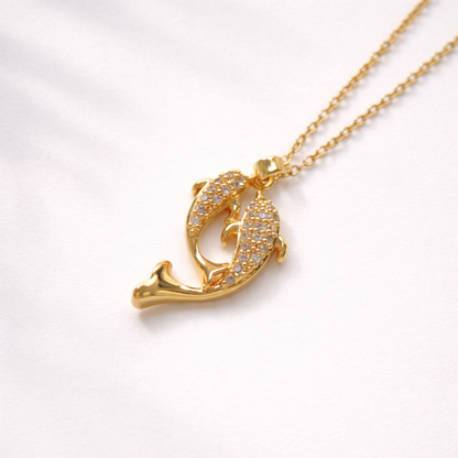 Gold dolphin pendant necklace on a white background