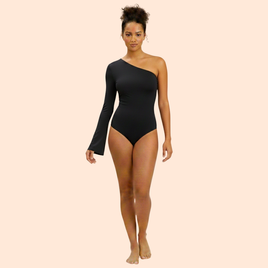 Woman wearing a black one-shoulder EB bodysuit on a beige background
