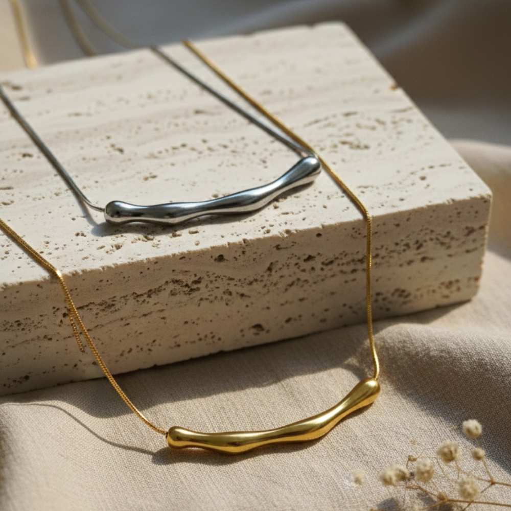 Gold necklace on a textured surface with a neutral background