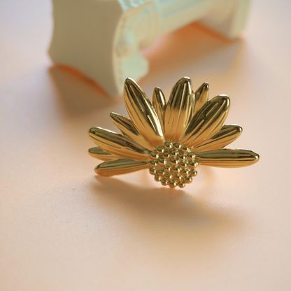 Gold sunflower-shaped earring on a light background