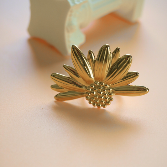 Gold sunflower-shaped earring on a light background