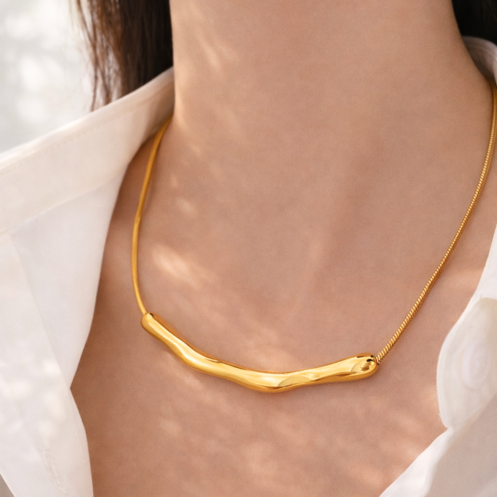Gold necklace worn by a person with a blurred background