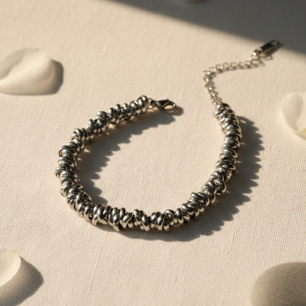 Silver beaded bracelet on a textured beige surface