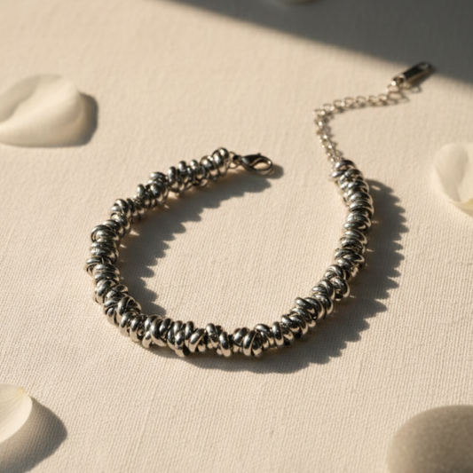 Silver beaded bracelet on a textured beige surface