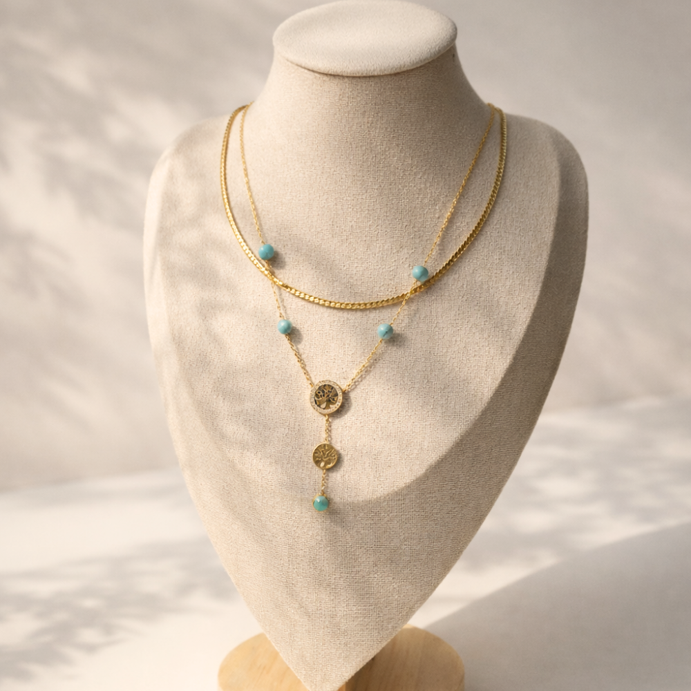 Gold necklace with turquoise beads on a mannequin bust against a neutral background