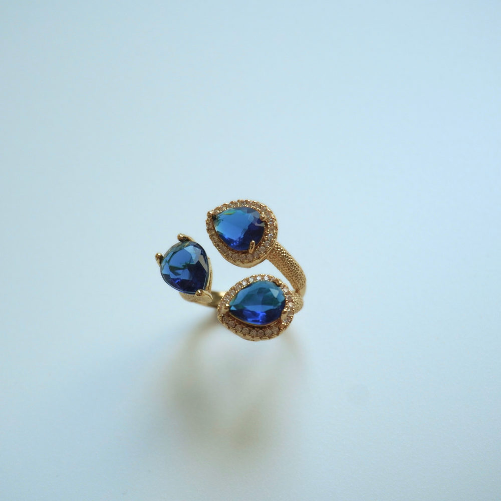 Gold ring with blue gemstones on a light blue background