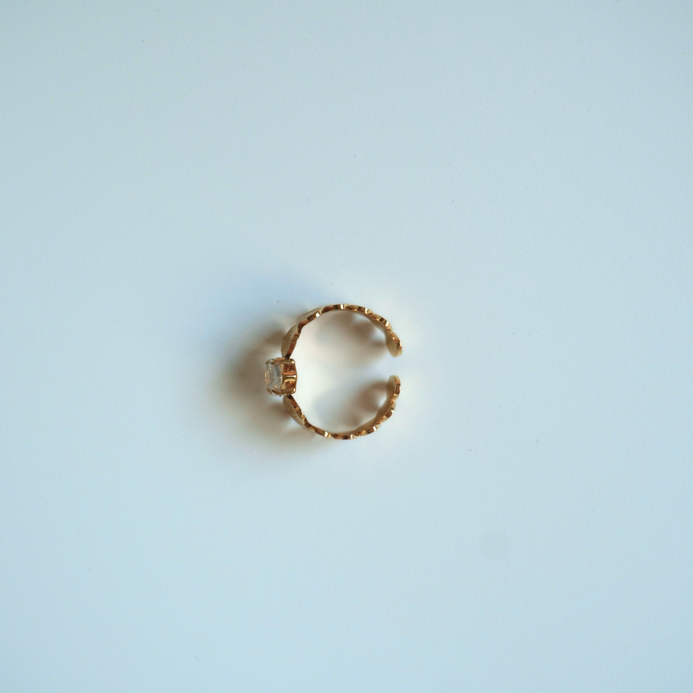 Gold ring with a central stone on a light blue background