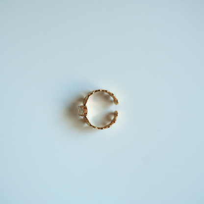 Gold ring with a central stone on a light blue background