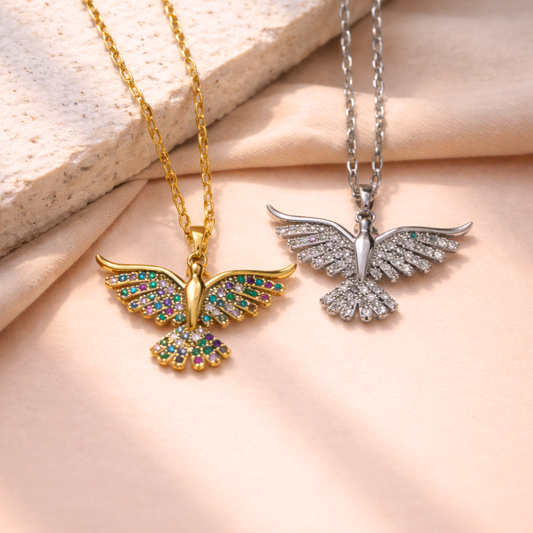 Two bird-shaped pendants on gold and silver chains against a beige fabric background
