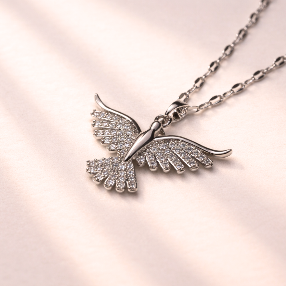 Bird-shaped necklace with gemstones on a light pink background