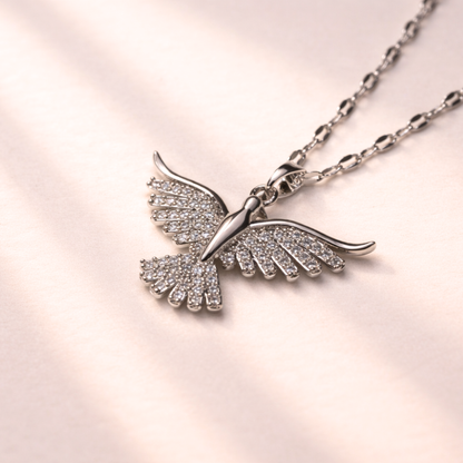 Bird-shaped necklace with gemstones on a light pink background