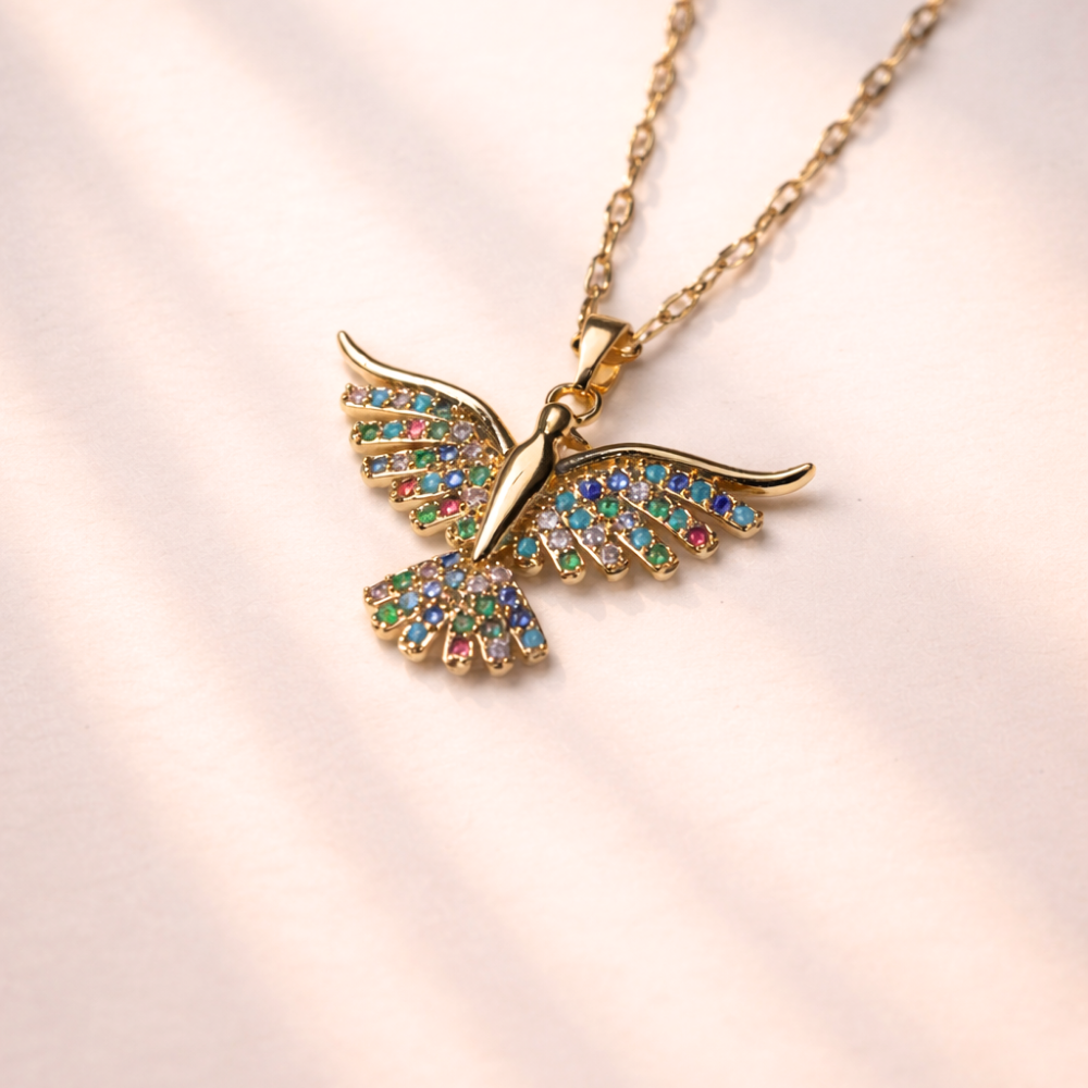 Bird-shaped necklace with colorful gemstones on a light pink background