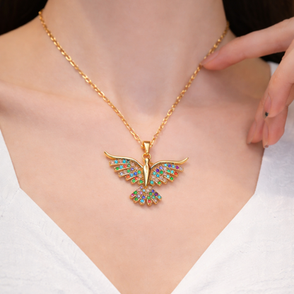 Gold bird necklace with colorful gemstones on a person wearing a white top.