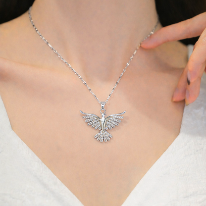 Silver bird pendant necklace on a person wearing a white top.