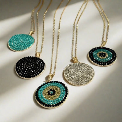 A collection of gold-plated necklaces with disk-shaped pendants. Some pendants have a black and white pattern, while others feature a geometric design with zircon stones.