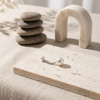 Pearl earring on a stone surface with stones and a marble sculpture in the background