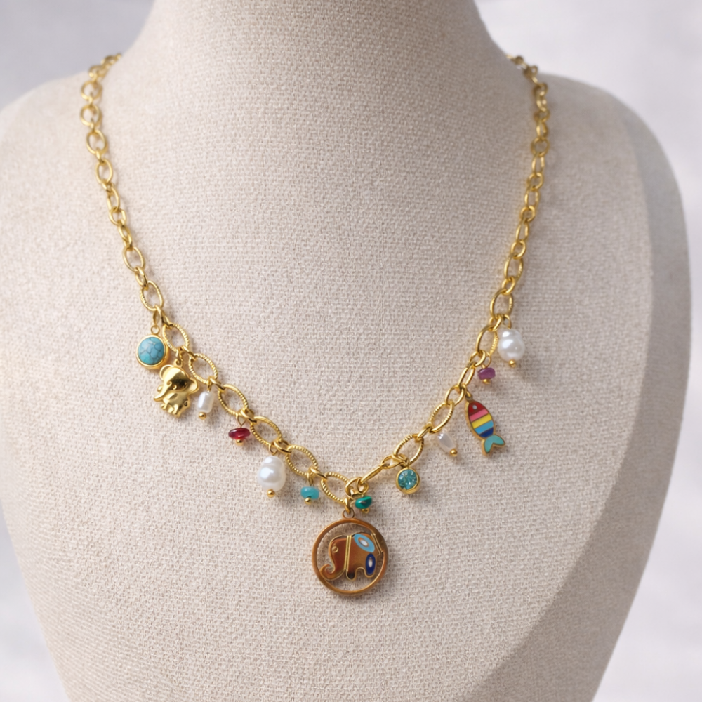 Gold necklace with various charms on a mannequin bust.