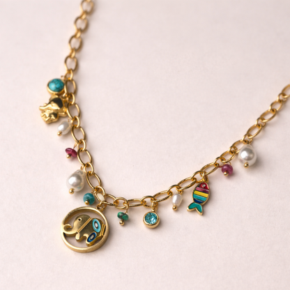 Gold necklace with various charms on a light pink background