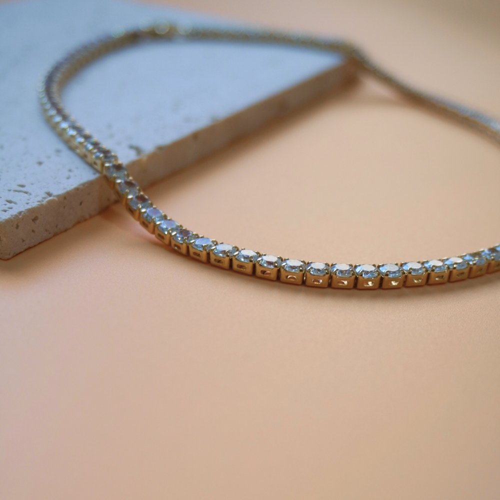 Zirconia tennis necklace with clear stones on a beige surface
