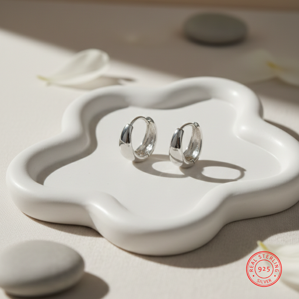 Silver hoop earrings on a white ceramic dish with 'Real Sterling 925' stamp.