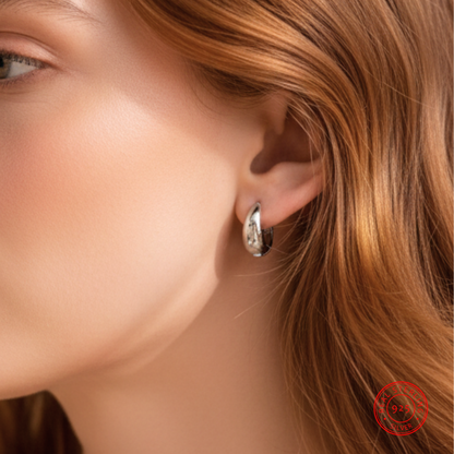 Close-up of a woman wearing a silver hoop earring with a blurred background