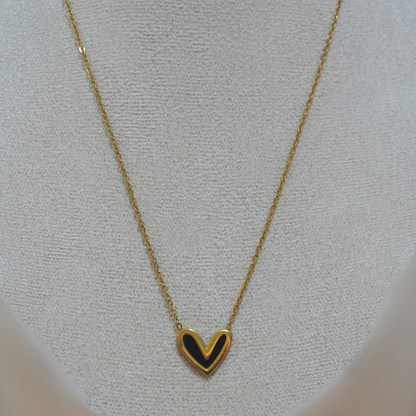 Gold necklace with a heart-shaped pendant on a light gray background