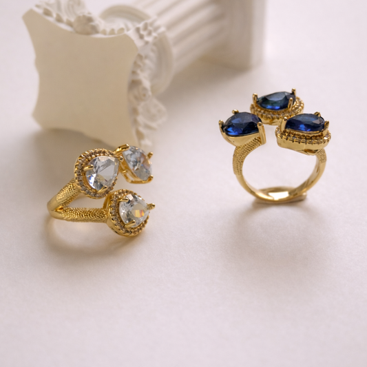 Two gold rings with gemstones on a light background