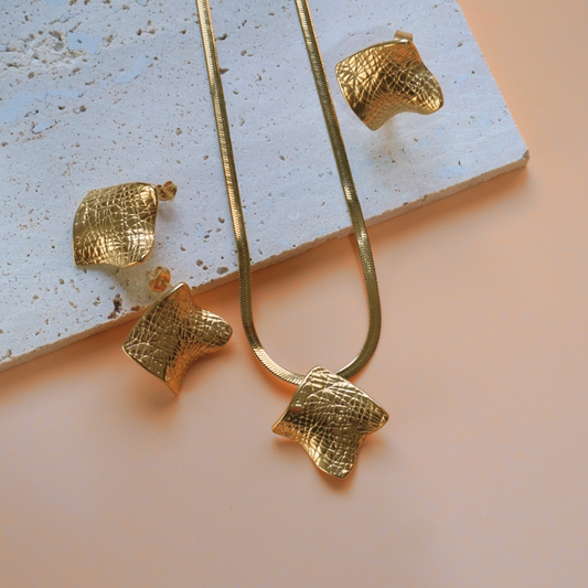 Gold earrings with textured design on a light surface