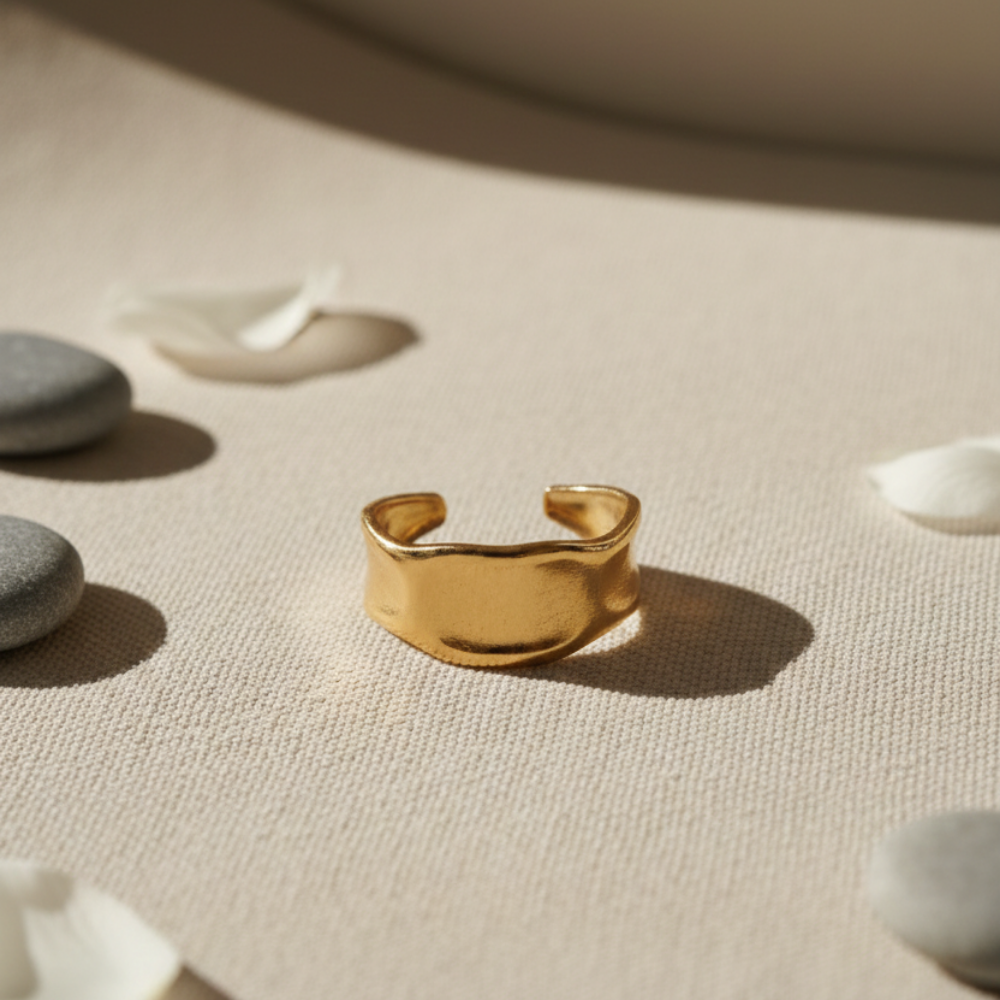 Gold ring on a textured beige surface with stones