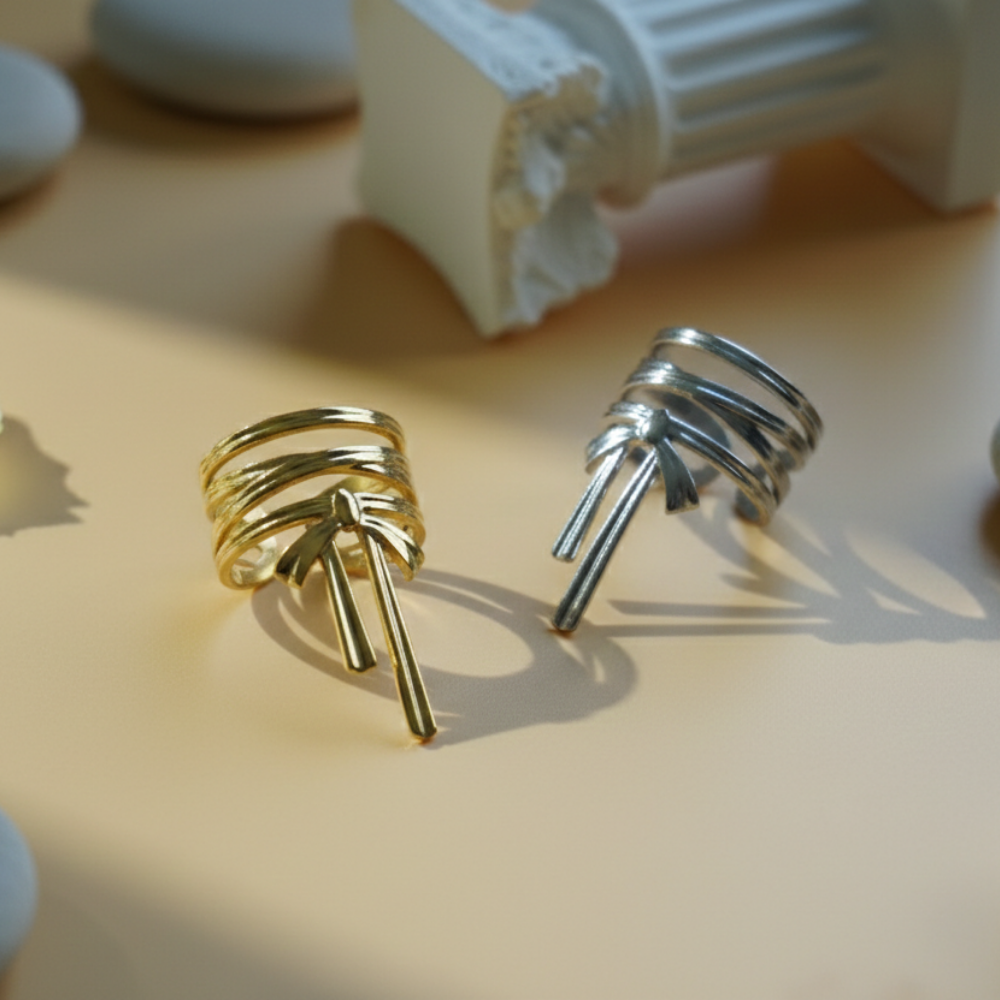 Gold and silver spiral earrings on a beige surface