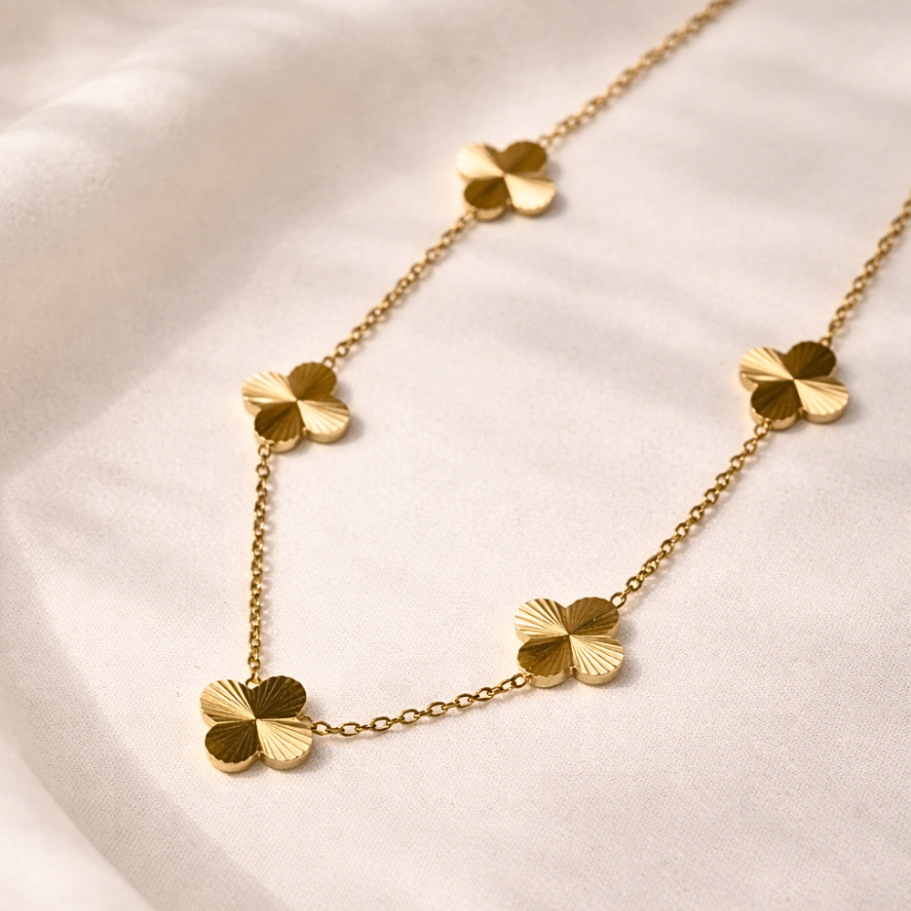 Gold necklace with clover-shaped pendants on a light background